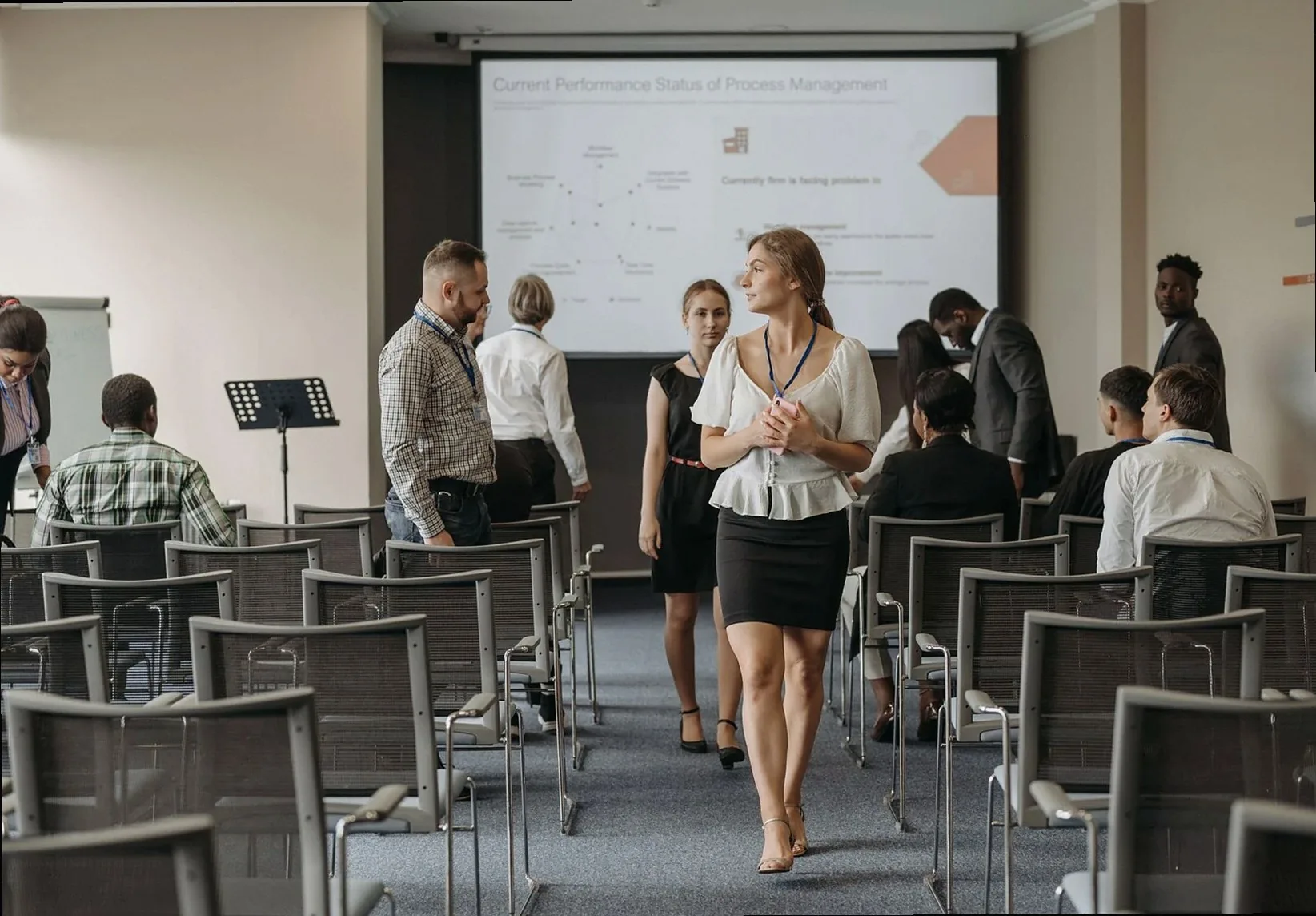 Professionals at a business conference engage before a presentation in a modern office.